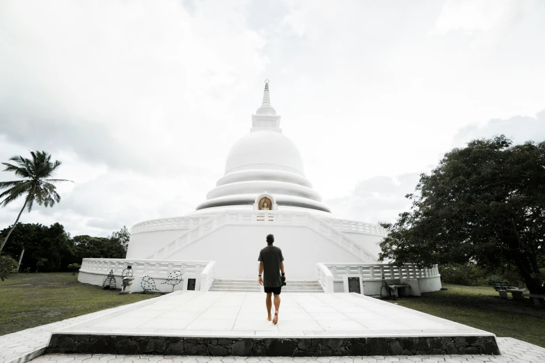 a person standing in front of a white building, pagoda, sri lankan landscape, walking towards the camera, dome