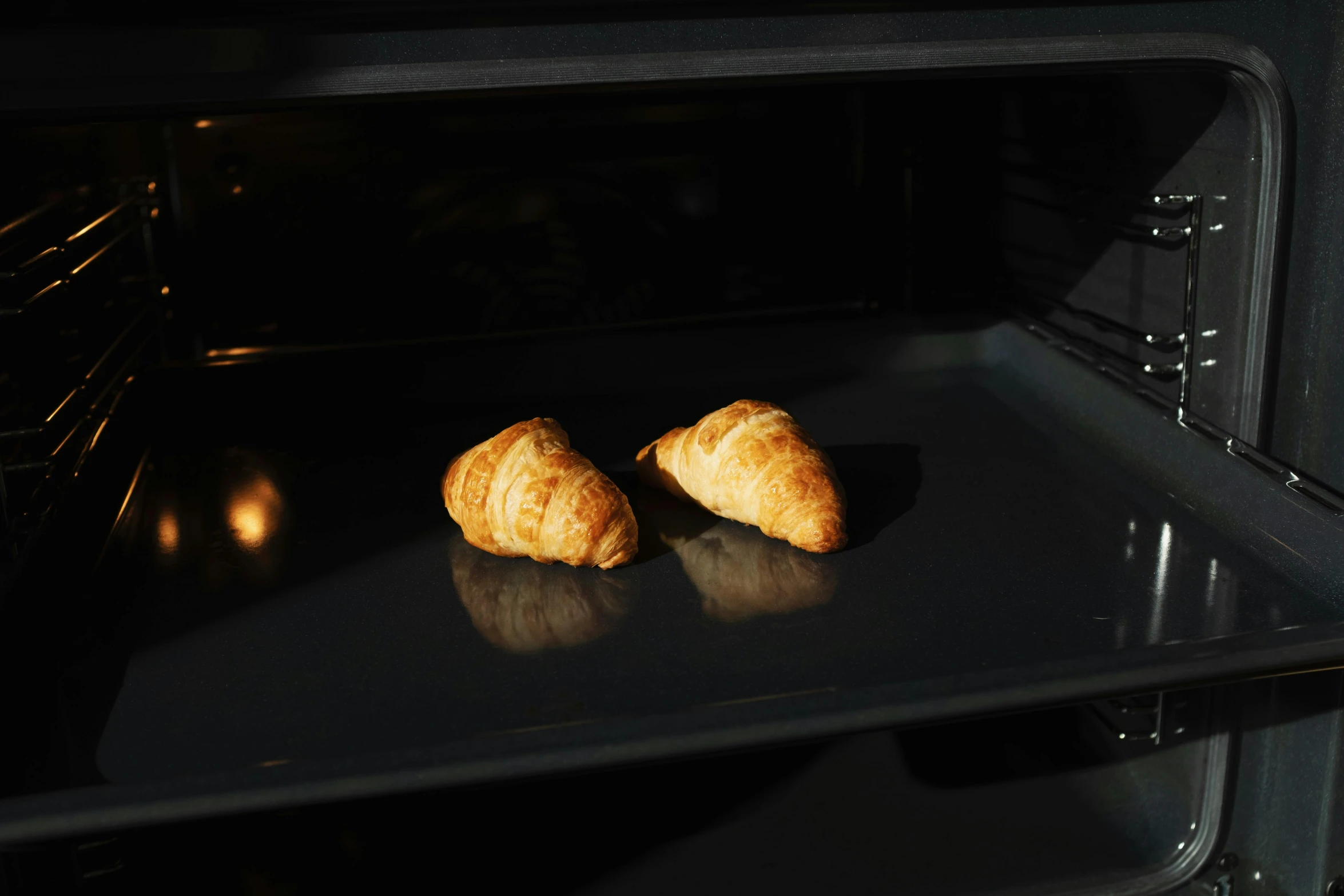 two croissants are baking in an oven, black matte finish, hasselblatt, unbeatable quality, 300mm