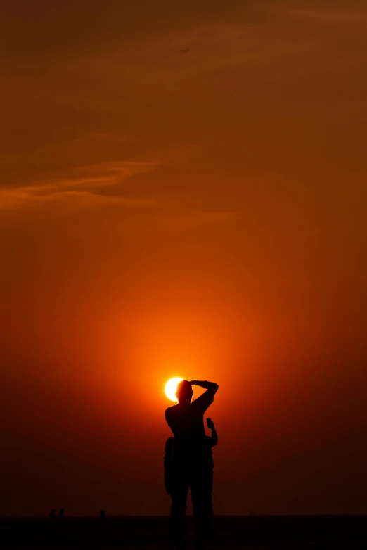 a person standing on a beach at sunset, by Sudip Roy, during an eclipse, phot, ap news photograph, two suns