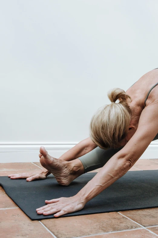 a woman doing a yoga pose on a mat, by Julian Allen, shows a leg, slate, leg and thigh shot, panoramic