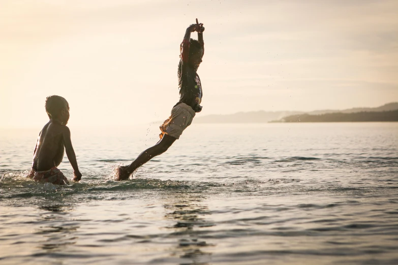 a couple of people that are in the water, by Jessie Algie, unsplash, jumping towards viewer, moana, kids playing, ignant