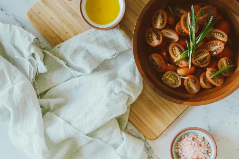 a bowl of tomatoes sitting on top of a wooden cutting board, by Carey Morris, trending on unsplash, white and pink cloth, olive oil, cloth wraps, background image