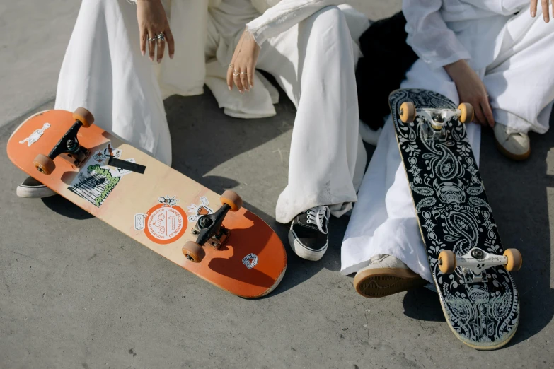 a couple of people sitting next to each other with skateboards, a picture, by Christen Dalsgaard, trending on unsplash, white and orange, paisley, ameera al-taweel, wedding