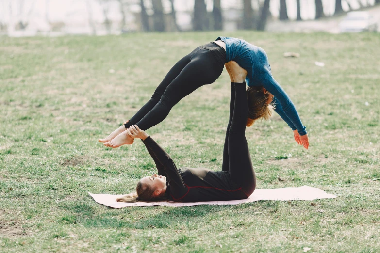 a woman doing a yoga pose in a park, pexels contest winner, arabesque, woman holding another woman, which splits in half into wings, avatar image, couple pose