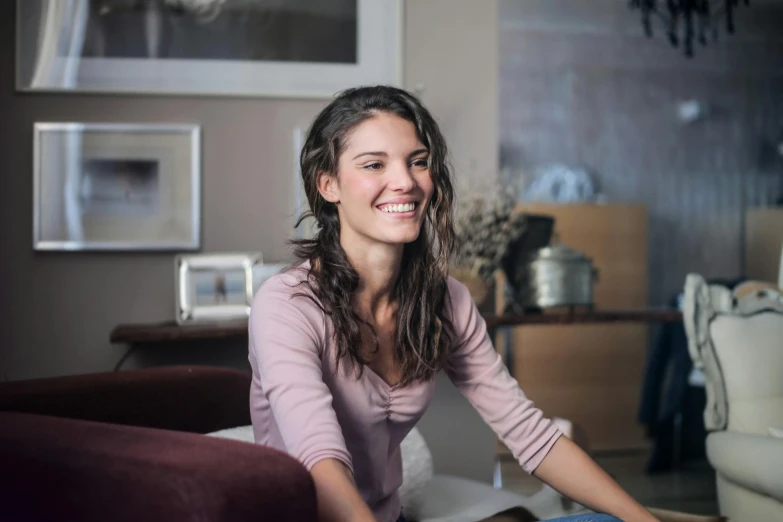 a woman sitting on a couch in a living room, pexels contest winner, pretty smile, italian looking emma, on a table, natural soft light