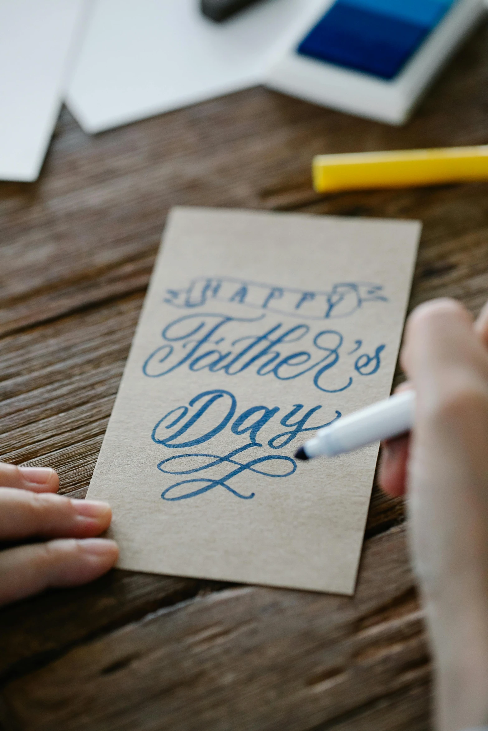 a person writing happy mother's day on a piece of paper, by Julia Pishtar, daddy/fatherly, tabletop, khakis, blue print