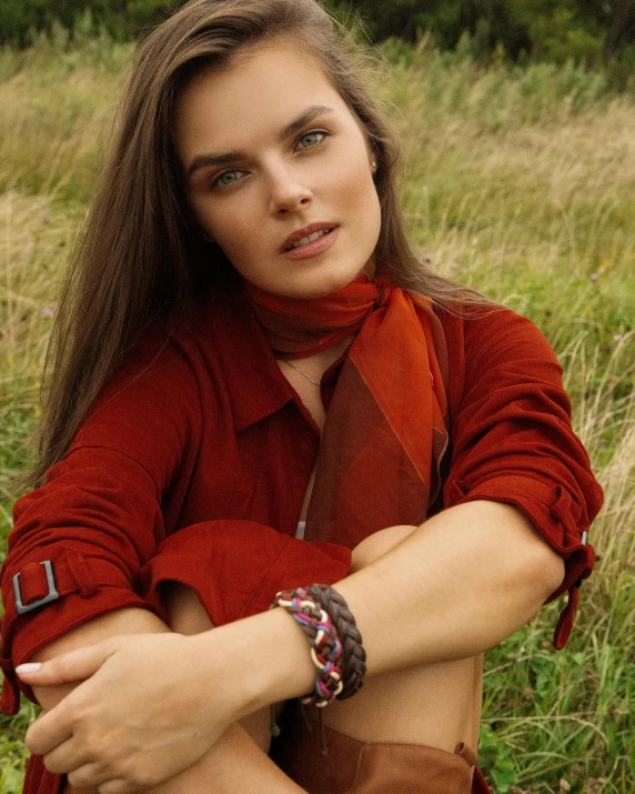 a beautiful young woman sitting on top of a lush green field, by Emma Andijewska, happening, bracelets, autumnal, rainbow, next to a red barn