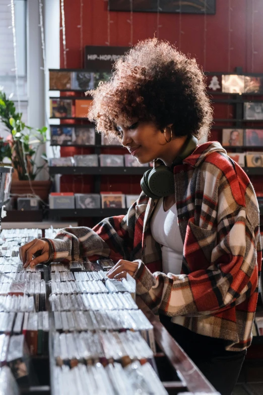 a woman sitting at a table with headphones on, an album cover, trending on pexels, black arts movement, girl in a record store, inspect in inventory image, mixing, satisfying