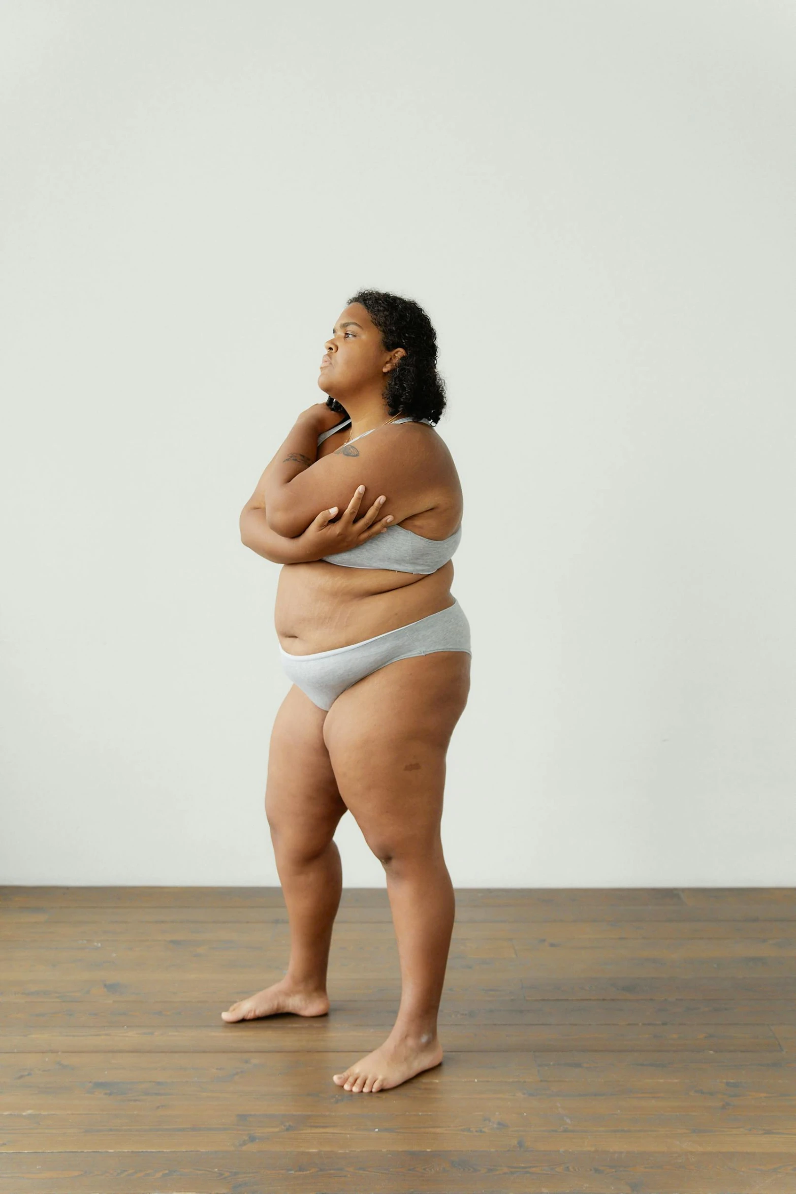 a woman in a bikini standing on a wooden floor, by Grace Polit, figuration libre, morbidly obese, on a gray background, promo image, wide film still