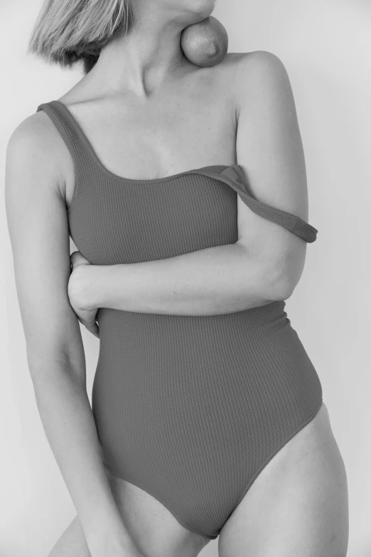 a black and white photo of a woman in a bodysuit, a black and white photo, by Gavin Hamilton, bandage on arms, closed swimsuit, desaturated color, soft curvy shape