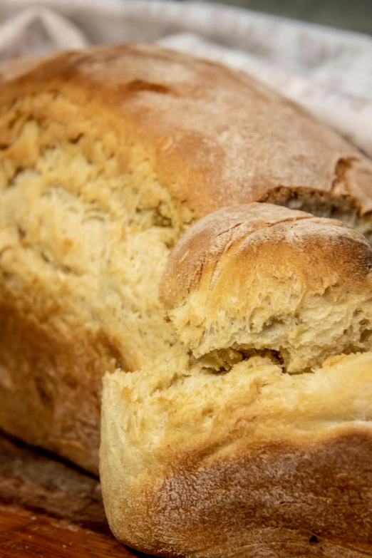 a loaf of bread sitting on top of a wooden cutting board, thumbnail, up-close, cream, frontal shot