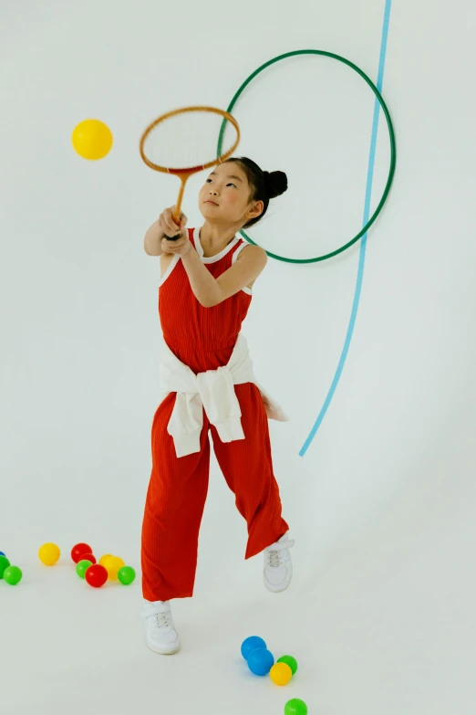 a woman in a red jumpsuit playing with a tennis racket, inspired by Gong Kai, gutai group, for kids, wearing a tracksuit, backdrop, hanging