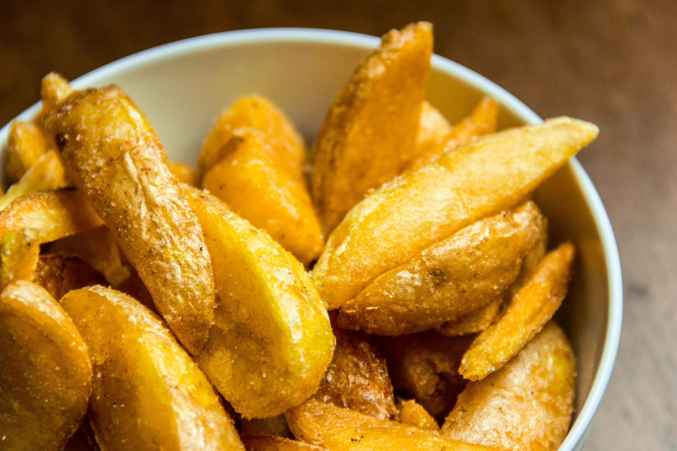 a bowl filled with french fries on top of a wooden table, te pae, thumbnail, skewed shot, crisps