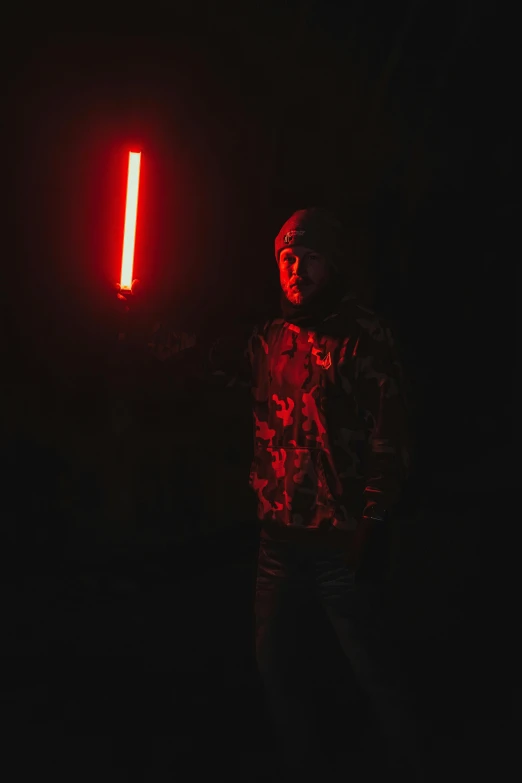 a man standing in the dark in front of a red light, holding an activated lightsaber, mrbeast, high quality photo
