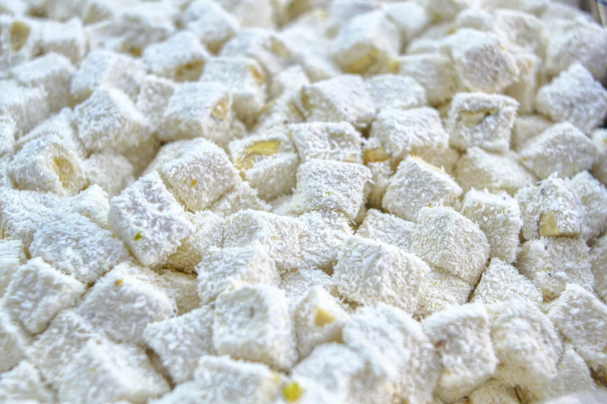 a close up of a plate of food covered in powdered sugar, irregularly shaped mosaic tiles, cubes, with lemon skin texture, lots of white cotton