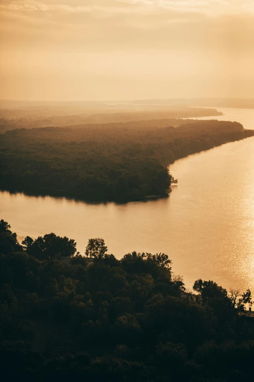 a large body of water surrounded by trees, by Adam Chmielowski, golden hour cinematic, high angle view, minn, massive river