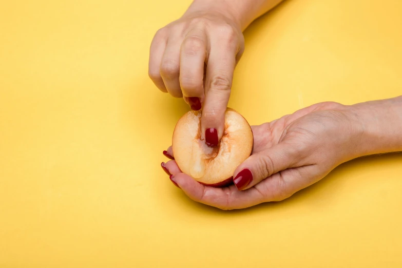 a person holding a piece of fruit in their hands, by Julia Pishtar, trending on pexels, hyperrealism, frying nails, peach, plain background, instructions