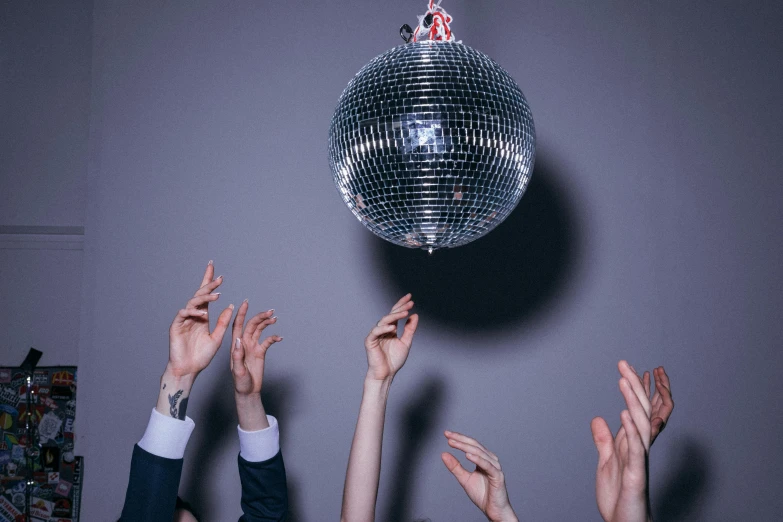 a group of people reaching up to catch a disco ball, an album cover, trending on pexels, fancy dress, sleek hands, mid-twenties, on grey background