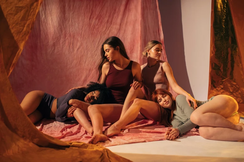 a group of women sitting on top of a bed, by Alice Mason, trending on pexels, renaissance, product shoot, warm hues, physical : tinyest midriff ever, angled view