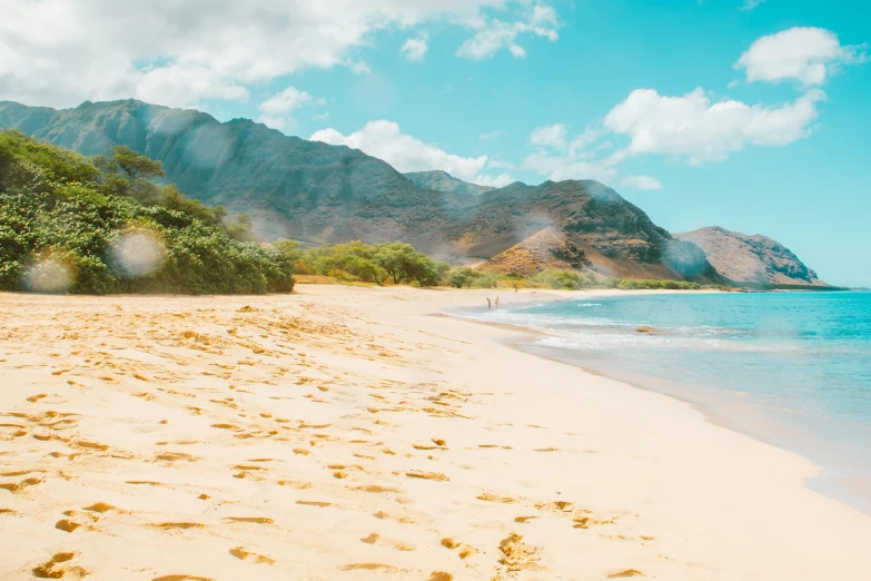 a sandy beach with a mountain in the background, trending on unsplash, hawaii beach, background image, sunfaded, conde nast traveler photo