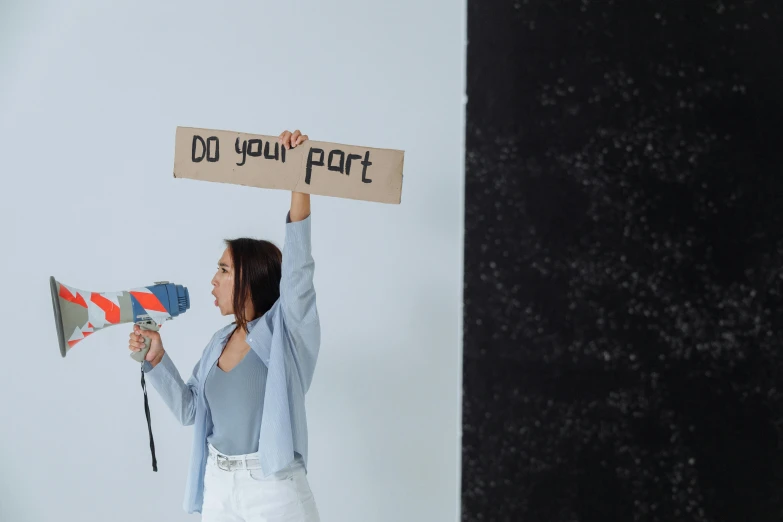 a woman holding a sign that says do your part, by Matija Jama, pexels contest winner, broken parts, chell from portal, holding a stuff, artem chebokha