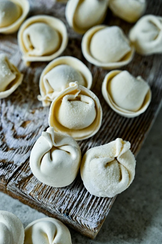 a wooden cutting board topped with dumplings on top of a table, unsplash, renaissance, thumbnail, white, pasta