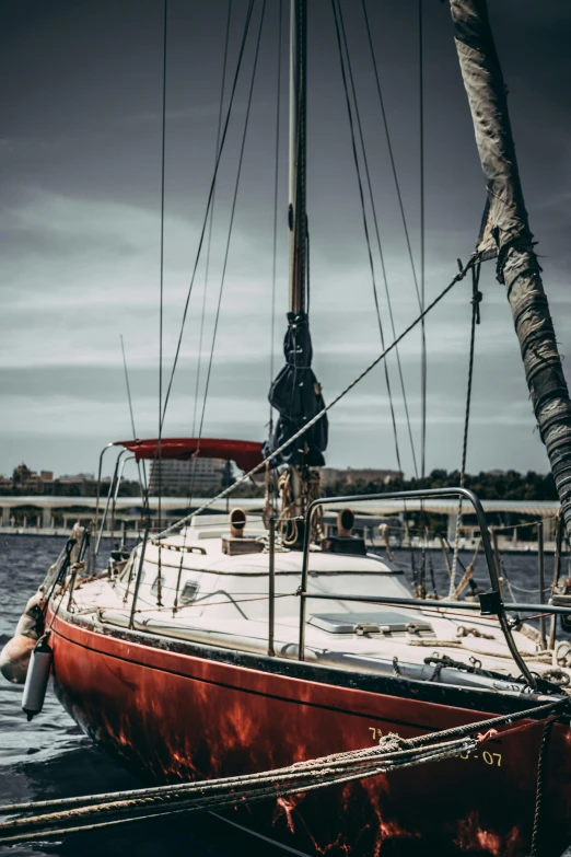 a red boat sitting on top of a body of water, sailing boat, outside