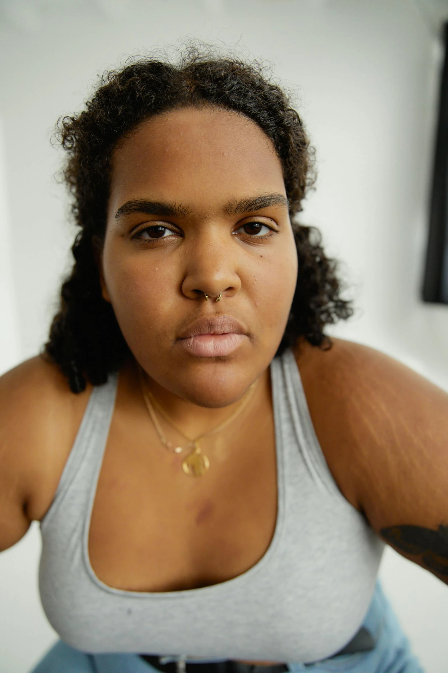 a close up of a person wearing a tank top, by artist, trending on unsplash, photorealism, lizzo, facial scar, transgender, someone in home sits in bed