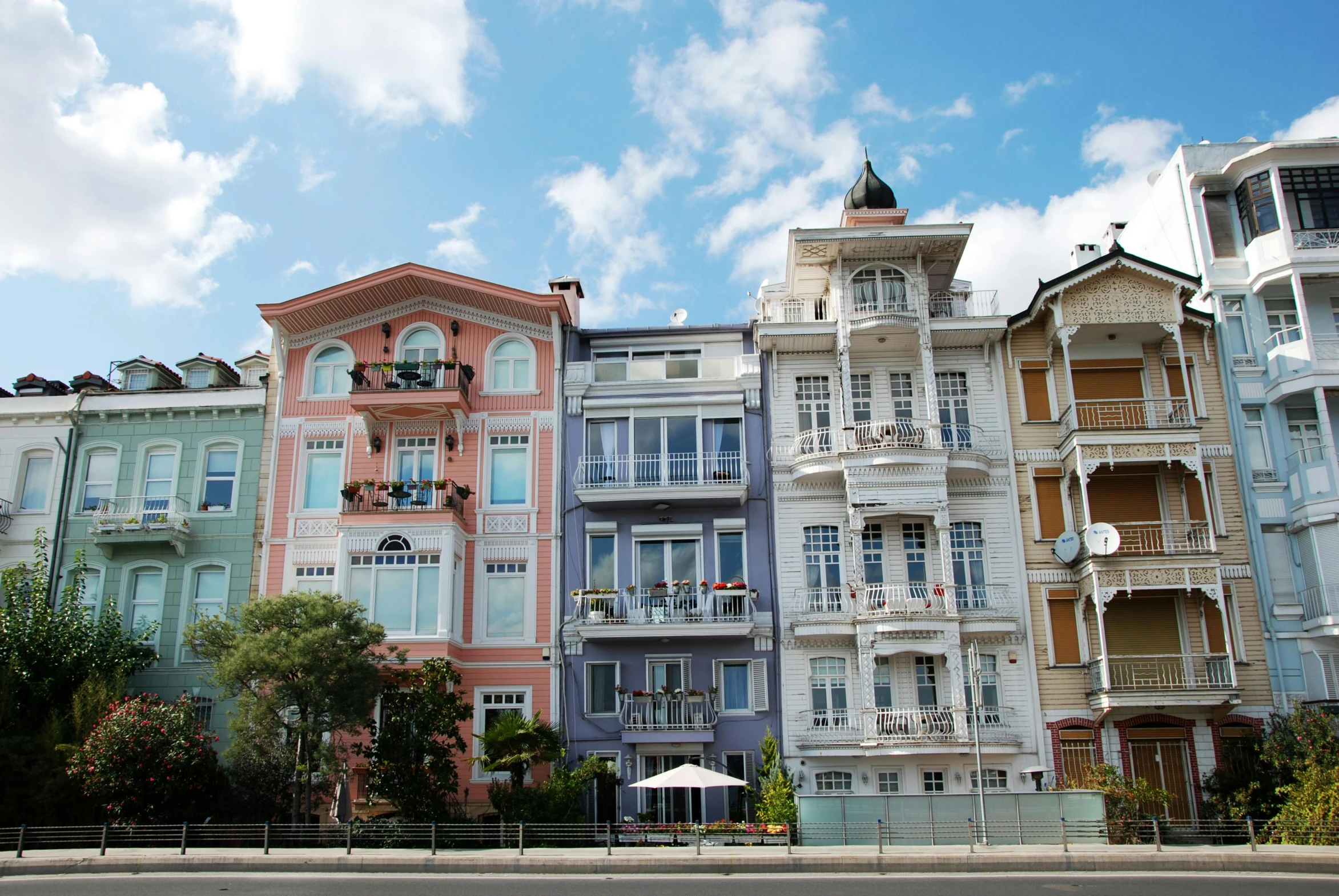 a row of multicolored buildings on a city street, a photo, inspired by Yasar Vurdem, unsplash, art nouveau, seaside, square, georgic, 3 pm