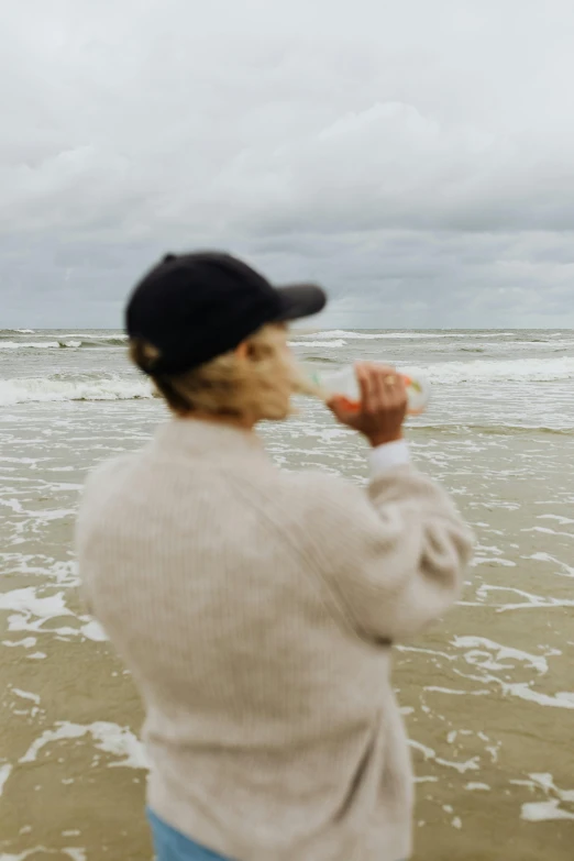 a woman standing on a beach flying a kite, by Jan Tengnagel, unsplash, visual art, wearing a baseball hat, low quality footage, blurred, profile image