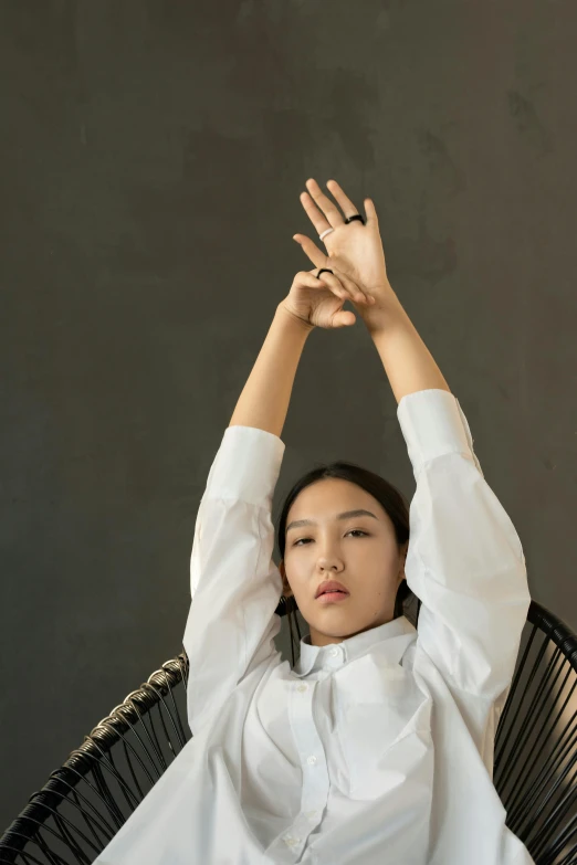 a woman sitting in a chair with her hands in the air, an album cover, inspired by Kim Tschang Yeul, unsplash, visual art, white shirts, asian human, sleek hands, portrait of a japanese teen
