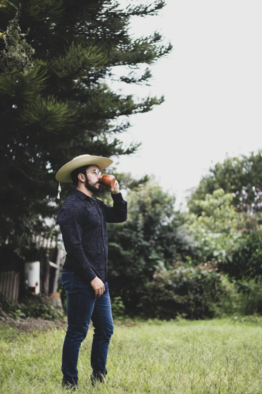 a man standing on top of a lush green field, an album cover, by Jessie Algie, pexels contest winner, getting his tacos and drink), bearded cowboy, coffee, profile pic