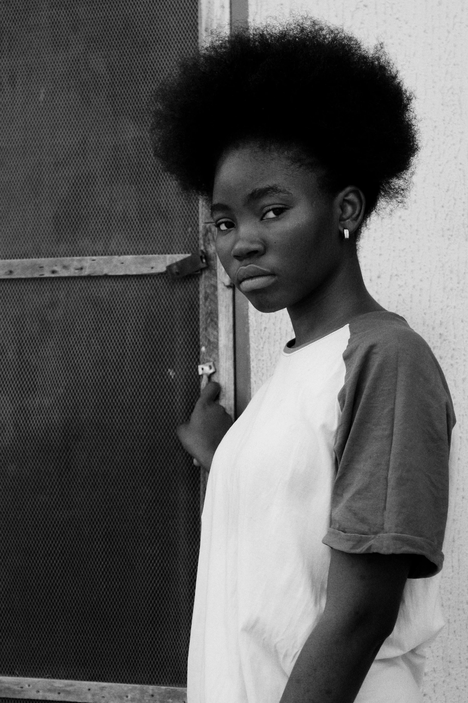 a black and white photo of a woman leaning against a wall, by Lily Delissa Joseph, 18 years old, afro tech, (beautiful) girl, with white skin