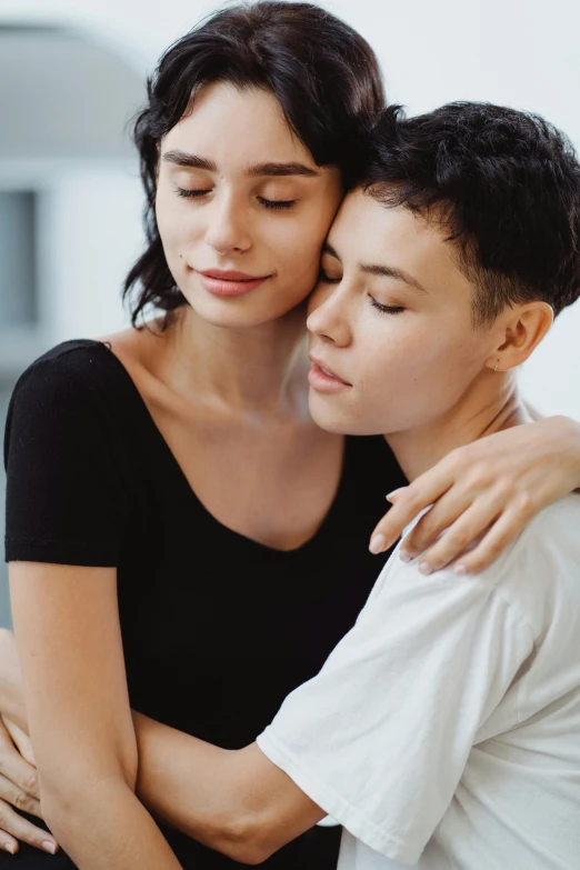 a woman hugging a boy who is sitting on a couch, trending on pexels, renaissance, lesbian embrace, mourning, two beautiful women in love, standing together