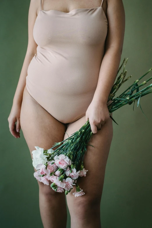 a woman in a bodysuit holding a bunch of flowers, by Elsa Bleda, unsplash, folds of belly flab, contracept, plump, thighs