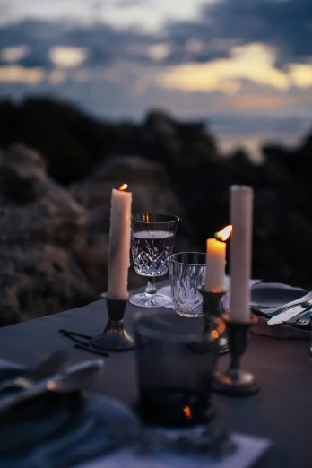 a couple of candles sitting on top of a table, on the ocean, eating outside, gentlemens dinner, garden setting