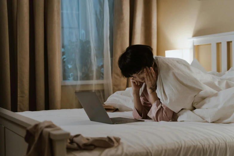 a woman laying in bed with a laptop, by Julia Pishtar, pexels contest winner, people crying, asian man, hotel room, youtube thumbnail