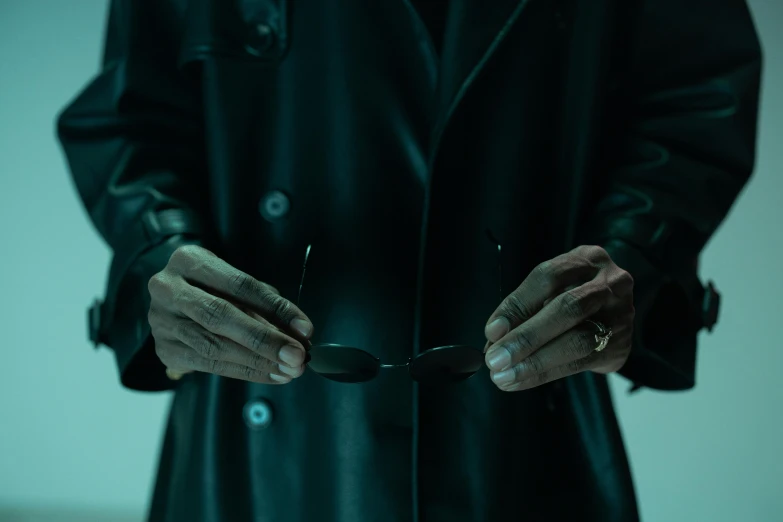 a man in a black coat holding a pair of scissors, inspired by John Carpenter, unsplash, still from loki ( 2 0 2 1 ), teal palette. horror, leather cuffs around wrists, rorschach