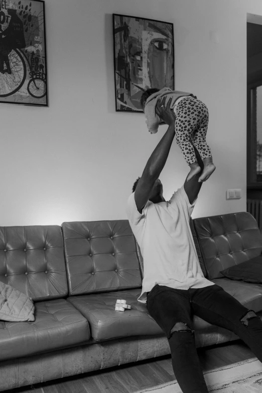 a black and white photo of a man holding a baby, by Caro Niederer, pexels contest winner, dada, an ahoge stands up on her head, sitting in a lounge, working out, black man