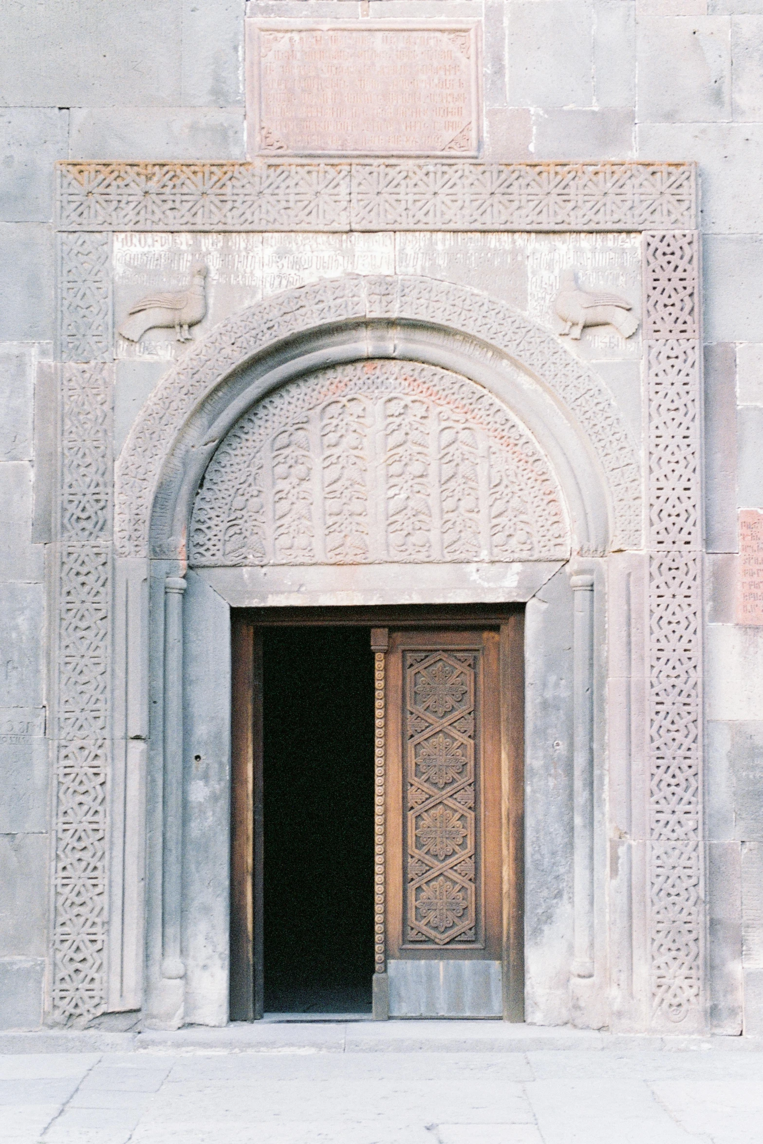 a couple of doors that are on the side of a building, inspired by Osman Hamdi Bey, romanesque, chiseled features, grey, tomb, patterned