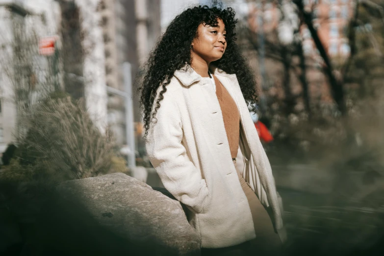 a woman with curly hair wearing a white coat, trending on pexels, sydney park, wearing jacket, trending photo, low - angle shot