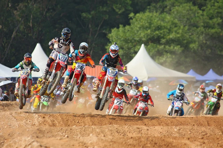 a group of people riding dirt bikes on a dirt track, tournament, 🚿🗝📝