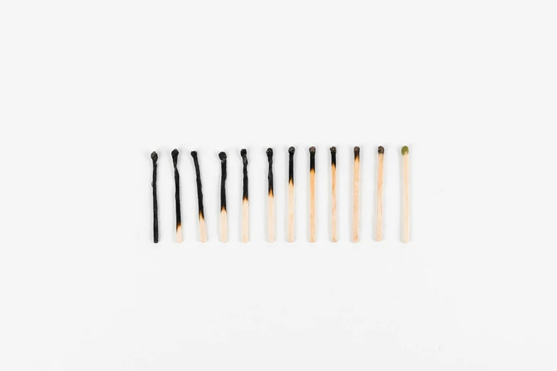 a row of matches on a white background, by Kristian Zahrtmann, auto-destructive art, gradient from green to black, natural straight black eyebrows, courtesy of moma, miniature product photo