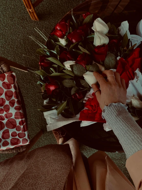 a woman holding a bouquet of red and white roses, an album cover, inspired by Elsa Bleda, trending on unsplash, romanticism, 😭 🤧 💔, holding hands, sitting on the floor, giving gifts to people