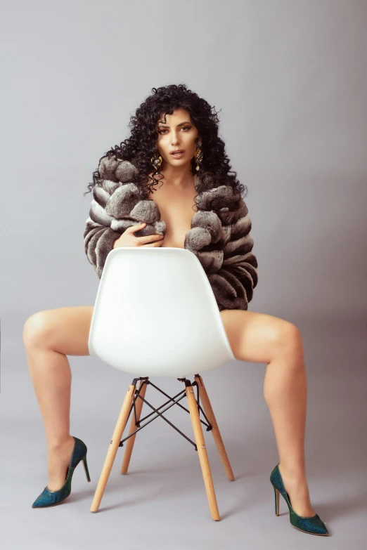 a woman sitting on top of a white chair, an album cover, inspired by Hedi Xandt, trending on pexels, long curly fur, wearing a grey fur robe, peter hurley, sunny leone