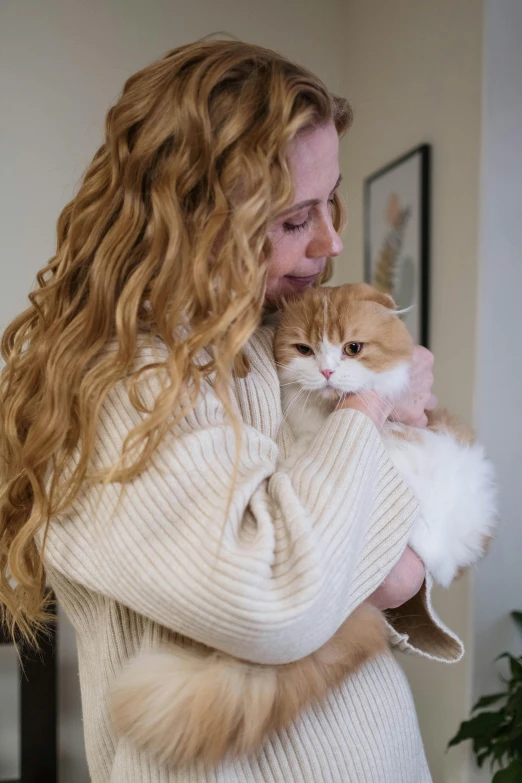 a woman holding a cat in her arms, trending on reddit, long curly blonde hair, cozy environment, hr ginger, profile image