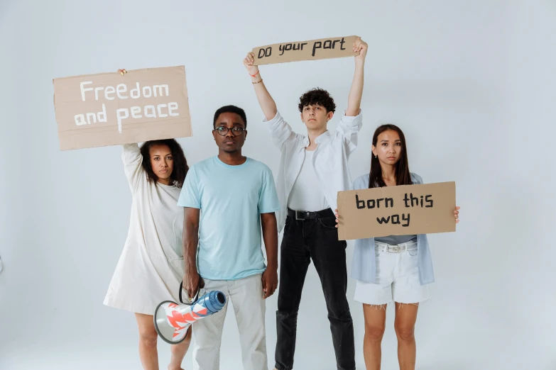 a group of people standing next to each other holding signs, trending on pexels, diverse costumes, teenage, background image, peacefull