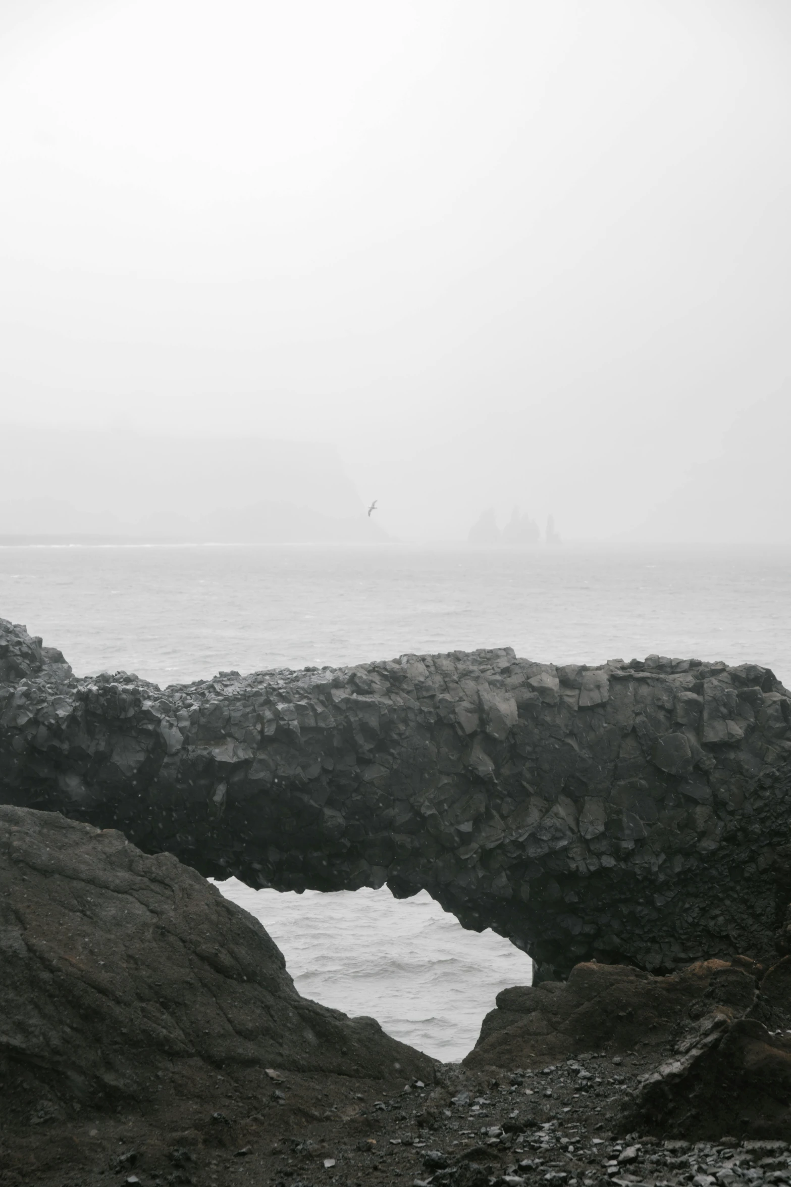 a black and white photo of a rock formation, inspired by Caspar David Friedrich, dark foggy water, mermaids in distance, reykjavik, low quality photo