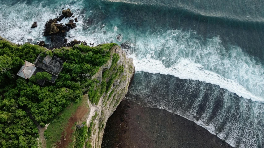 a house sitting on top of a cliff next to the ocean, pexels contest winner, drone view, bali, ((waves, grey