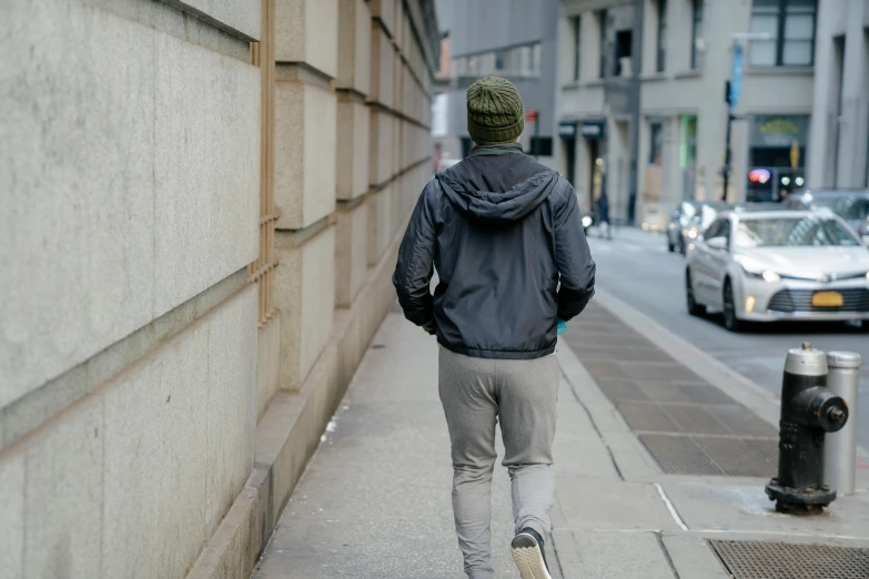 a man riding a skateboard down a sidewalk, by Nina Hamnett, pexels contest winner, happening, grey hoodie, walking away, beanie, north melbourne street